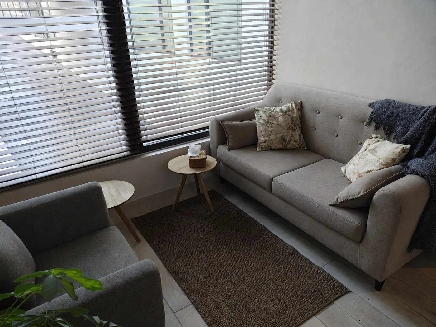 Sala de atención luminosa con sofá gris y sillón
